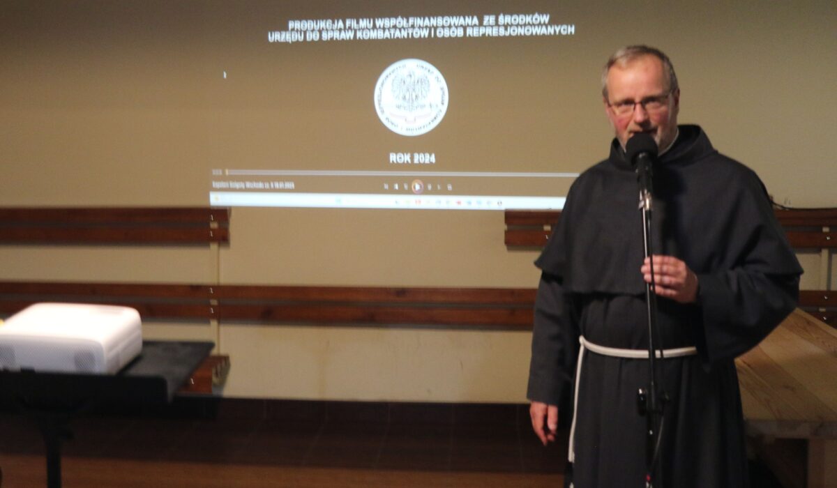 Franciszkanin przemawia przy mikrofonie podczas spotkania w Instytucie Maryjno-Kolbiańskim „Kolbianum” w Niepokalanowie