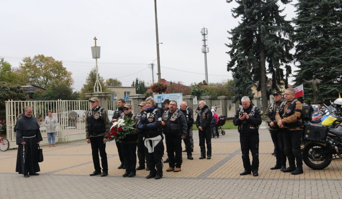Uczestnicy Rajdu Katyńskiego i franciszkanin z kwiatami przy pomniku św. Maksymiliana Kolbego w Niepokalanowie