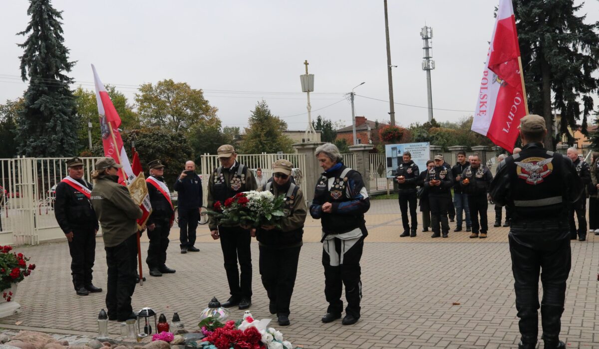 Uczestnicy Rajdu Katyńskiego z biało-czerwonymi flagami składają kwiaty i znicze pod pomnikiem św. Maksymiliana Kolbego